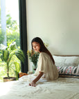 A serene morning moment with the Solara Linen Bedspread, draping the bed in soft, handwoven elegance. Sunlight filters through the window, highlighting the delicate embroidery that adds a touch of artistry and warmth to the space.