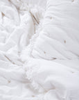 The Celestial Sky Bedspread, a luxurious handwoven cotton creation, showcases delicate hand-embroidered star motifs scattered across its soft, textured surface. The gentle fringe detailing along the edges adds an airy, ethereal touch, making it the perfect layer for a serene and inviting bedroom.