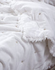 The Celestial Sky Bedspread, a luxurious handwoven cotton creation, showcases delicate hand-embroidered star motifs scattered across its soft, textured surface. The gentle fringe detailing along the edges adds an airy, ethereal touch, making it the perfect layer for a serene and inviting bedroom.