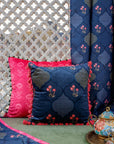 Nargis Cushion Cover – A luxurious fusion of cotton and velvet, this cushion cover features an intricate floral and geometric motif in rich navy blue, highlighted with delicate pink accents. Handcrafted with exceptional detail, its plush texture and vibrant tassel edging add a regal charm to any space.