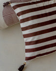 Ember Glow Cushion Cover – A striking cotton cushion cover featuring bold, hand-block-printed stripes in warm earthy tones. Finished with elegant tassels and wooden bead detailing, this artisanal piece adds depth and texture to any space, celebrating traditional craftsmanship with a modern aesthetic.