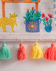 Climber Height Chart – A beautifully handcrafted cotton height chart featuring a vibrant illustration of a wooden plant shelf adorned with lush greenery, colorful pots, and playful garden elements like a straw hat, dragonfly, and butterfly. Hand-stitched details add texture and charm, making it a delightful keepsake for tracking growth milestones.