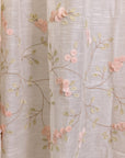 Elegantly Draped Curtains – A delicate, handcrafted curtain made from fine, textured fabric, adorned with intricate hand embroidery and soft pink floral appliqués. Each flower is carefully stitched with subtle detailing, creating a graceful and refined design. The flowing branches and leaves add a natural, organic touch, making these curtains a timeless addition to any elegant home setting.