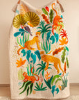 A handcrafted quilt titled The Forest is My Playground, featuring a vibrant jungle scene with hand-painted and stitched details. The quilt showcases playful monkeys swinging through lush green foliage, majestic cheetahs moving gracefully, and a toucan perched beneath oversized tropical leaves. The intricate design, rich in color and texture, is set against a soft cream background, bringing warmth and liveliness to any space.