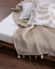 The Ethereal Silk Throw, a luxurious handwoven creation made from the finest mulberry silk. Its soft, rippled texture and delicate tassels exude refinement, draping effortlessly over a bed for a serene, elegant touch.