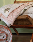 The Trees of Wonder Quilt, crafted from handwoven cotton, features intricate hand-block printed tree motifs that evoke a sense of natural serenity. The soft, quilted texture offers warmth and comfort, while the reversible striped pattern adds versatility to its timeless design. A perfect blend of artistry and coziness for an inviting bedroom.