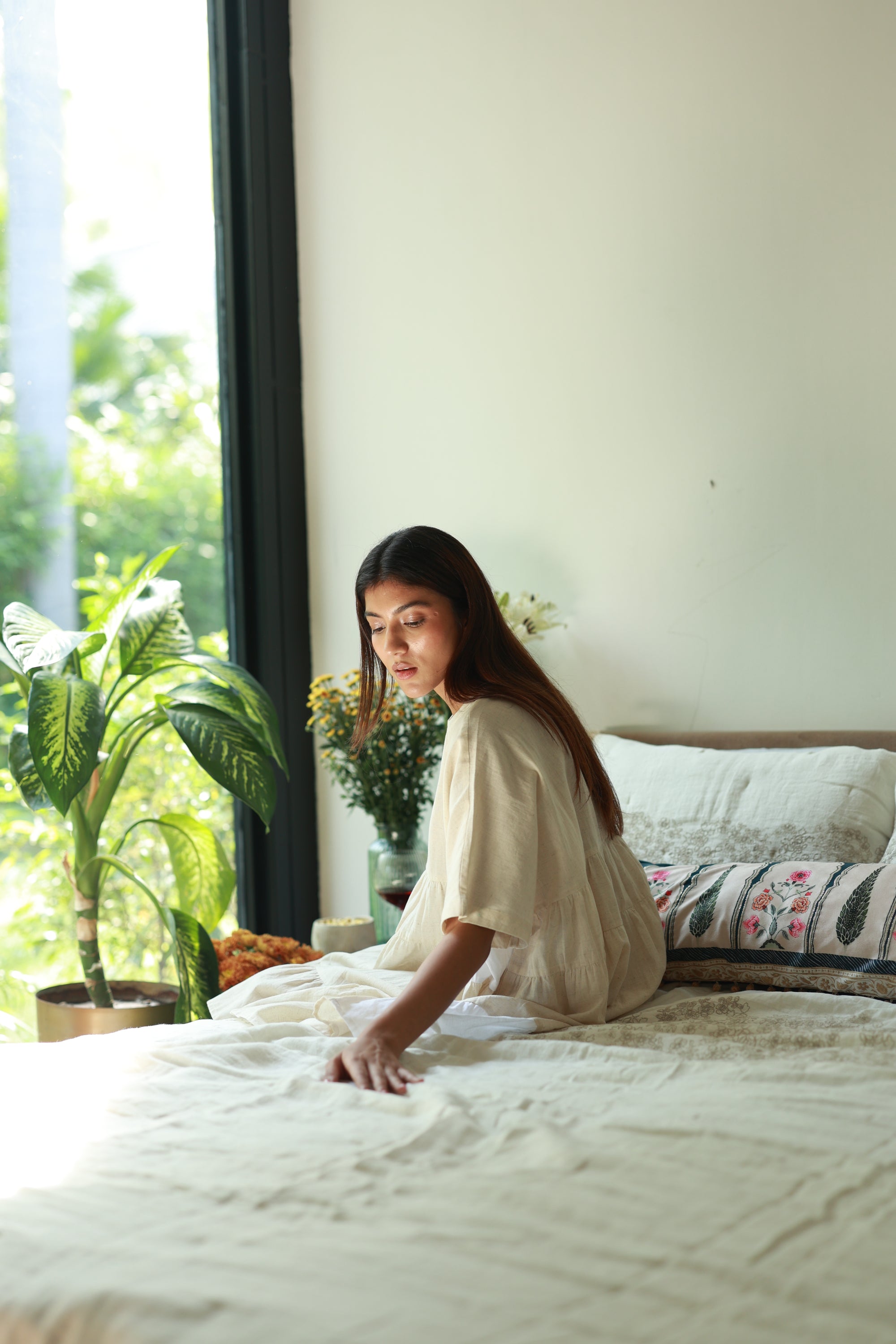 A serene morning moment with the Solara Linen Bedspread, draping the bed in soft, handwoven elegance. Sunlight filters through the window, highlighting the delicate embroidery that adds a touch of artistry and warmth to the space.