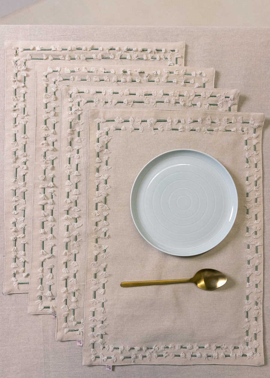 Tassled Table Mat – This handwoven cotton table mat is elevated with delicate hand embroidery and tassel detailing, creating a refined yet artisanal touch for your dining space. Its soft texture and intricate craftsmanship add warmth and sophistication to every meal.