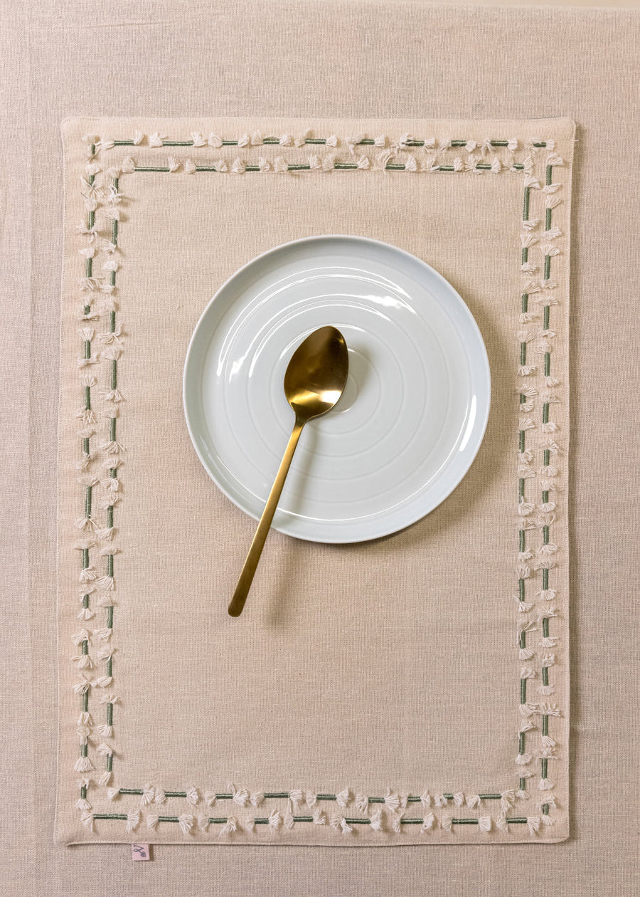 Tassled Table Mat – This handwoven cotton table mat is elevated with delicate hand embroidery and tassel detailing, creating a refined yet artisanal touch for your dining space. Its soft texture and intricate craftsmanship add warmth and sophistication to every meal.