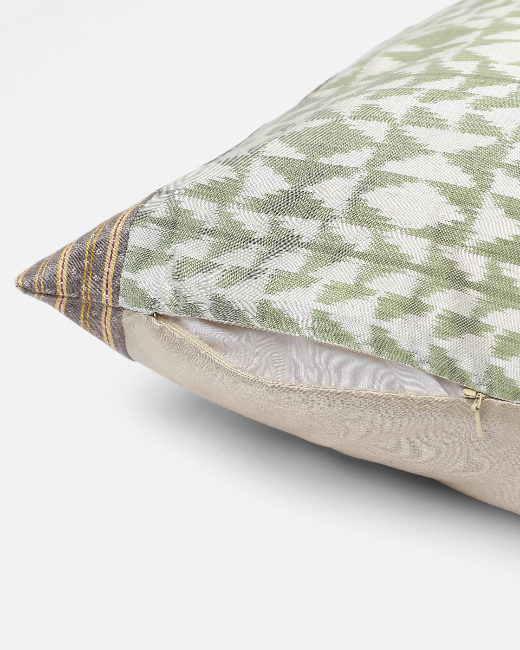 Vivia Cushion Cover – A refined blend of silk and cotton, this cushion cover showcases an intricate ikat-inspired pattern in soft sage green and ivory. Handwoven with exceptional craftsmanship, its delicate striped borders add a touch of elegance. A versatile piece that enhances both contemporary and traditional spaces.