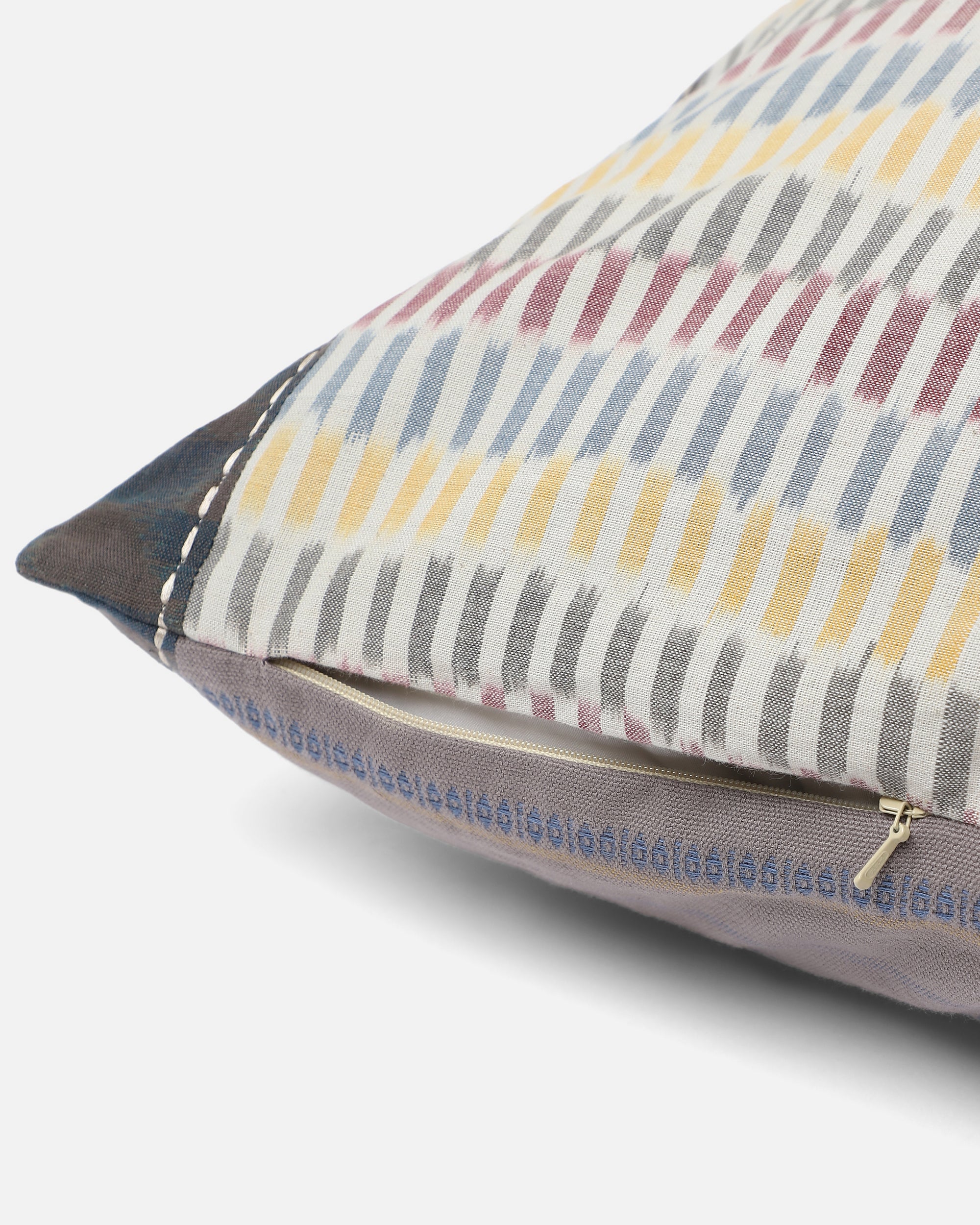 Sofia Cushion Cover – A beautifully handwoven cotton cushion cover featuring a subtle ikat-inspired pattern in warm, earthy tones of yellow, grey, and burgundy. Finished with delicate hand-stitched detailing and a contrasting dark-hued border, this piece embodies craftsmanship and understated elegance. Perfect for adding texture and character to any living space.