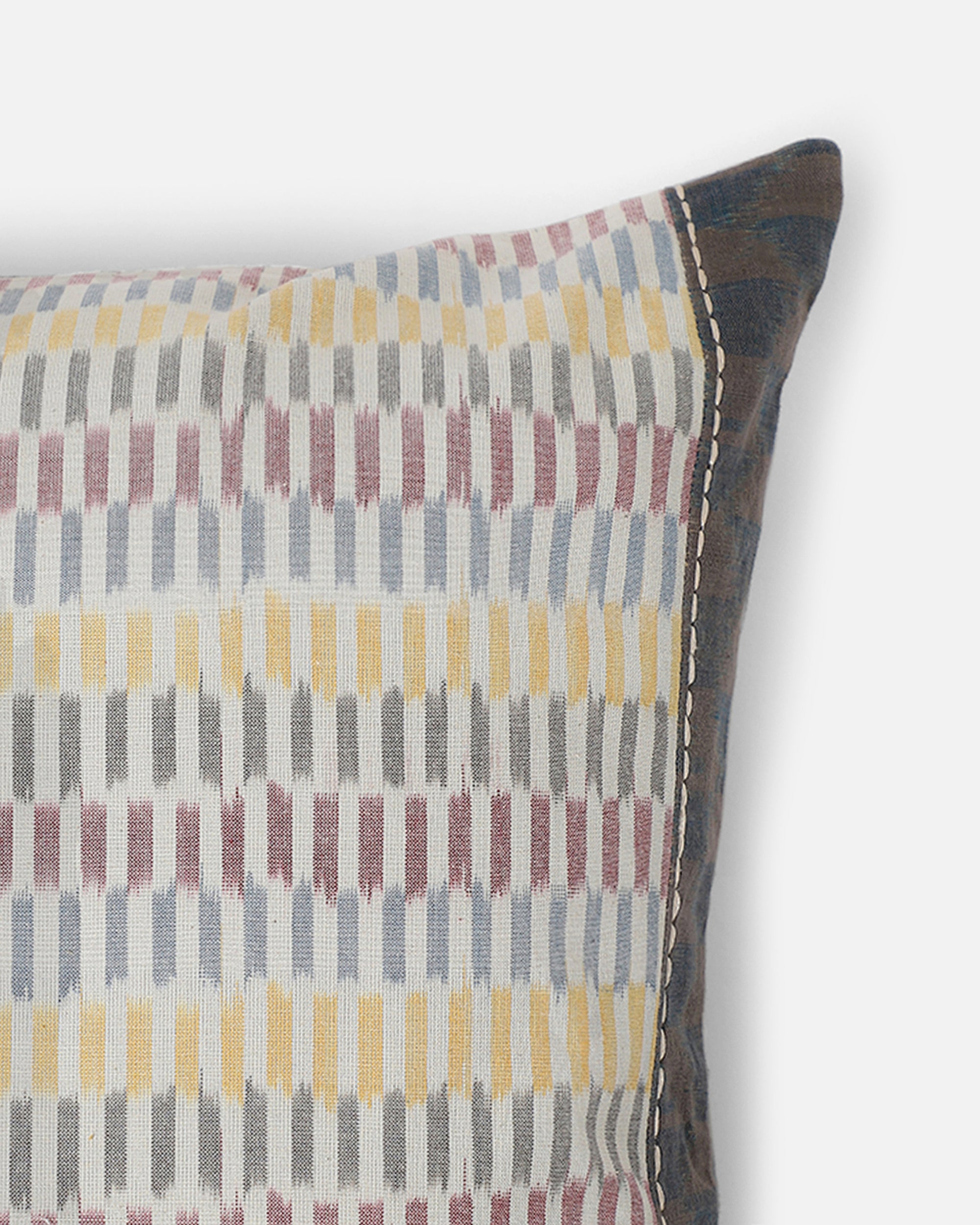 Sofia Cushion Cover – A beautifully handwoven cotton cushion cover featuring a subtle ikat-inspired pattern in warm, earthy tones of yellow, grey, and burgundy. Finished with delicate hand-stitched detailing and a contrasting dark-hued border, this piece embodies craftsmanship and understated elegance. Perfect for adding texture and character to any living space.
