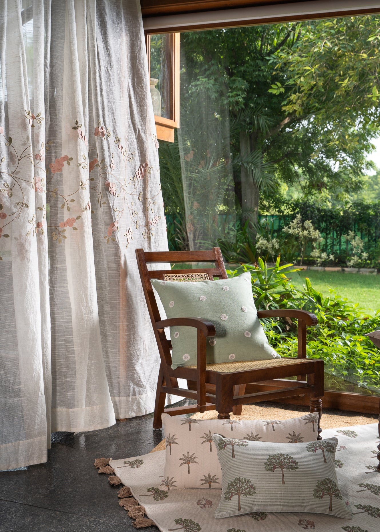 Elegantly Draped Curtains – A delicate, handcrafted curtain made from fine, textured fabric, adorned with intricate hand embroidery and soft pink floral appliqués. Each flower is carefully stitched with subtle detailing, creating a graceful and refined design. The flowing branches and leaves add a natural, organic touch, making these curtains a timeless addition to any elegant home setting.