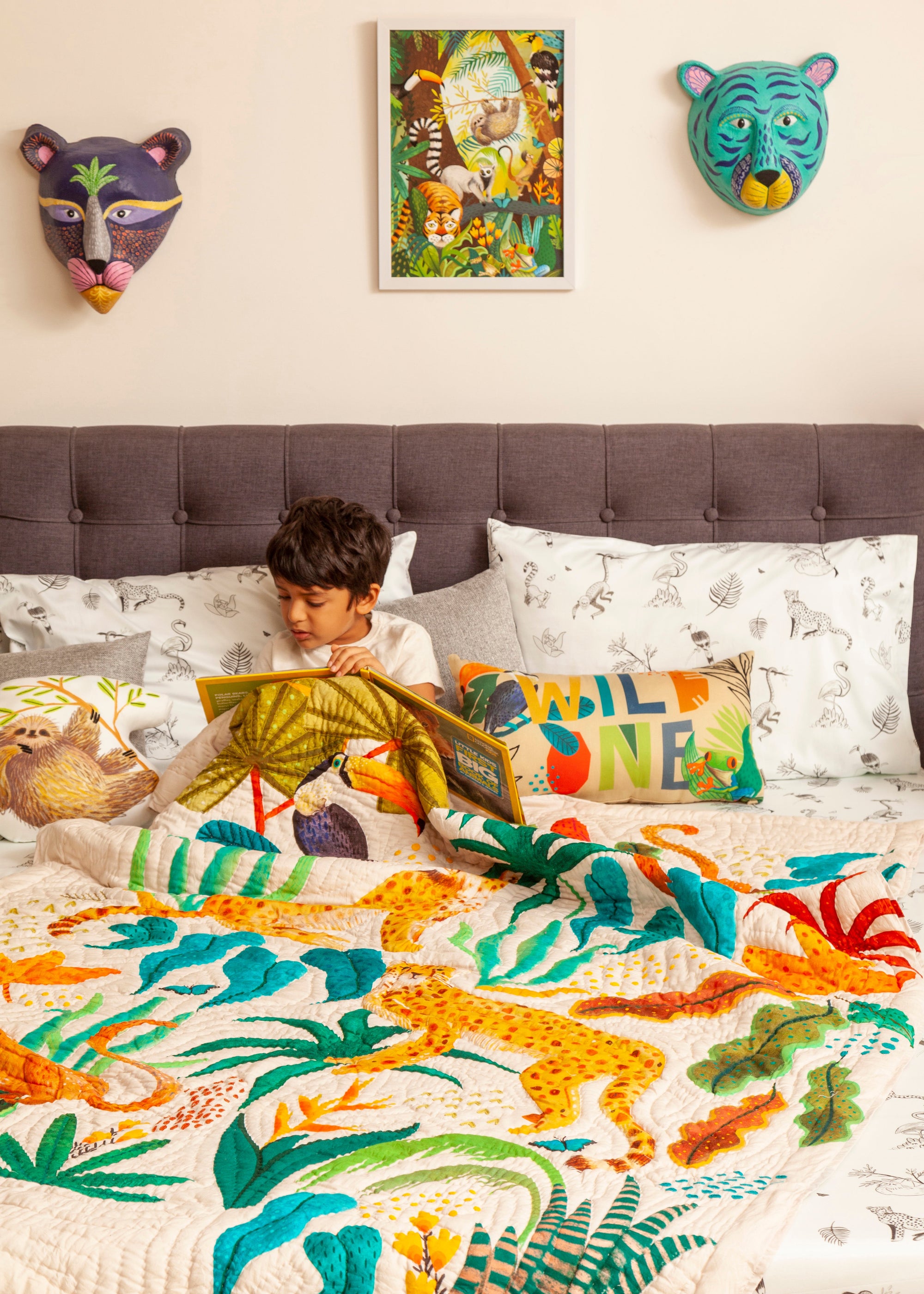 A handcrafted quilt titled The Forest is My Playground, featuring a vibrant jungle scene with hand-painted and stitched details. The quilt showcases playful monkeys swinging through lush green foliage, majestic cheetahs moving gracefully, and a toucan perched beneath oversized tropical leaves. The intricate design, rich in color and texture, is set against a soft cream background, bringing warmth and liveliness to any space.