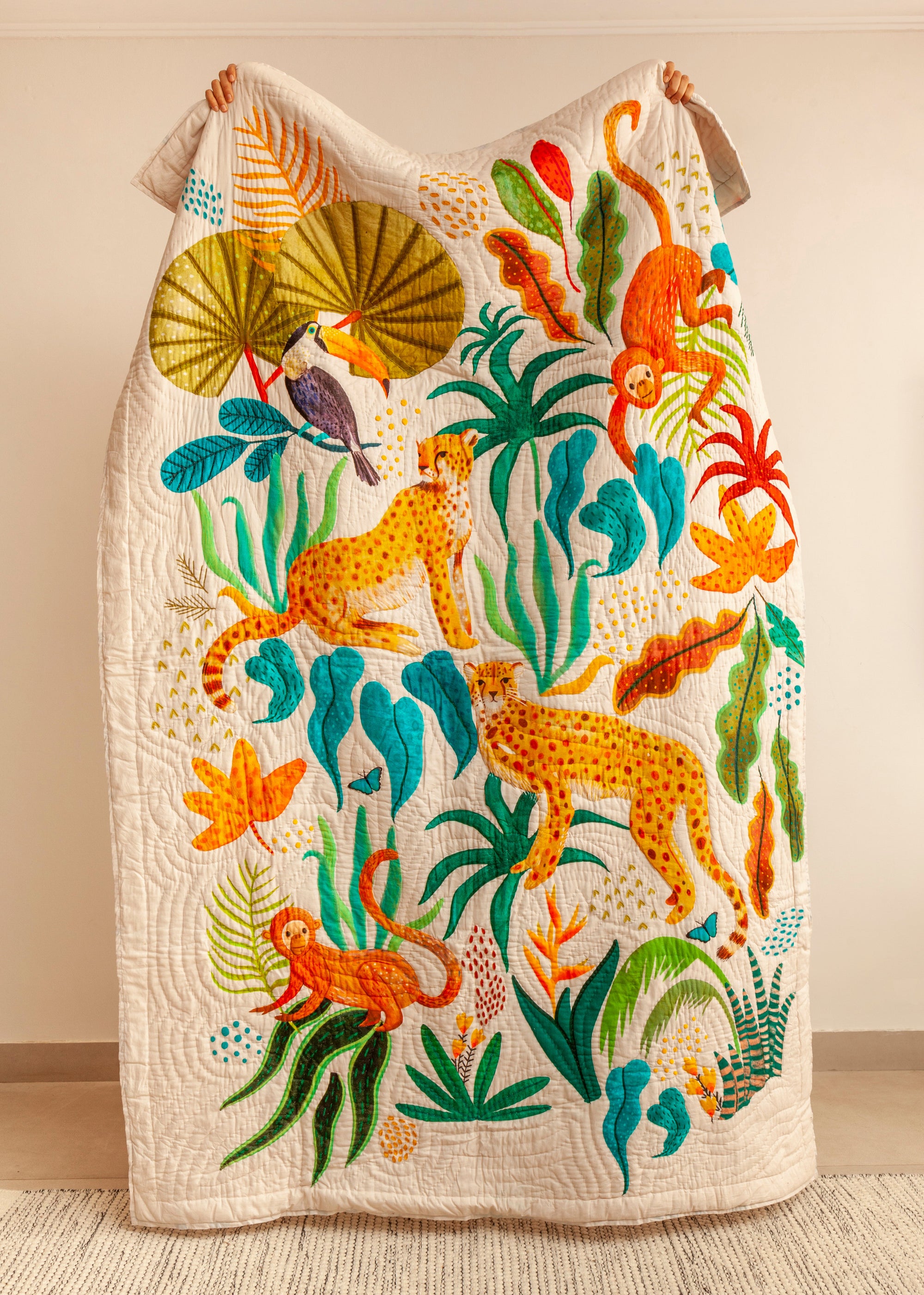 A handcrafted quilt titled The Forest is My Playground, featuring a vibrant jungle scene with hand-painted and stitched details. The quilt showcases playful monkeys swinging through lush green foliage, majestic cheetahs moving gracefully, and a toucan perched beneath oversized tropical leaves. The intricate design, rich in color and texture, is set against a soft cream background, bringing warmth and liveliness to any space.