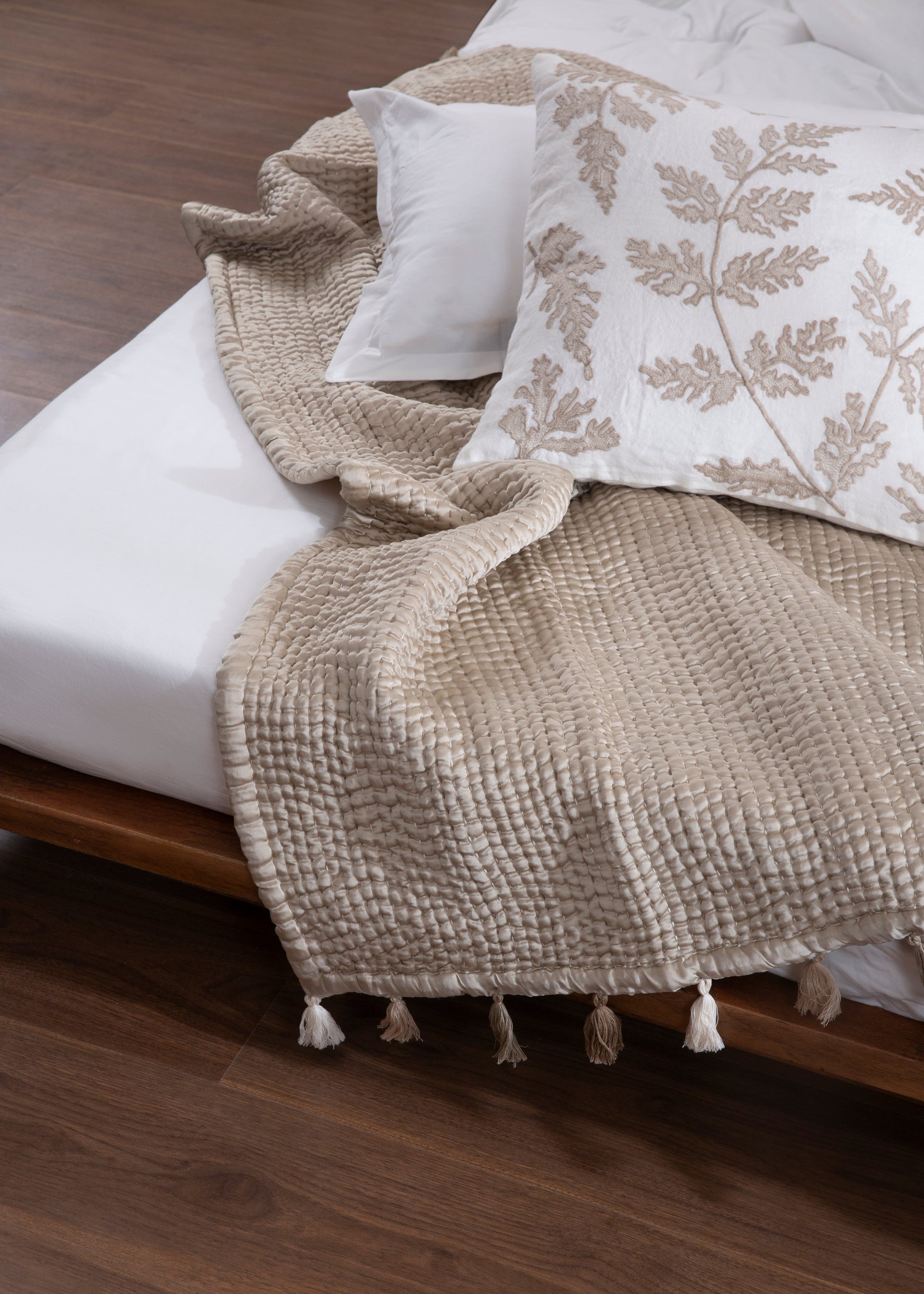 The Ethereal Silk Throw, a luxurious handwoven creation made from the finest mulberry silk. Its soft, rippled texture and delicate tassels exude refinement, draping effortlessly over a bed for a serene, elegant touch.