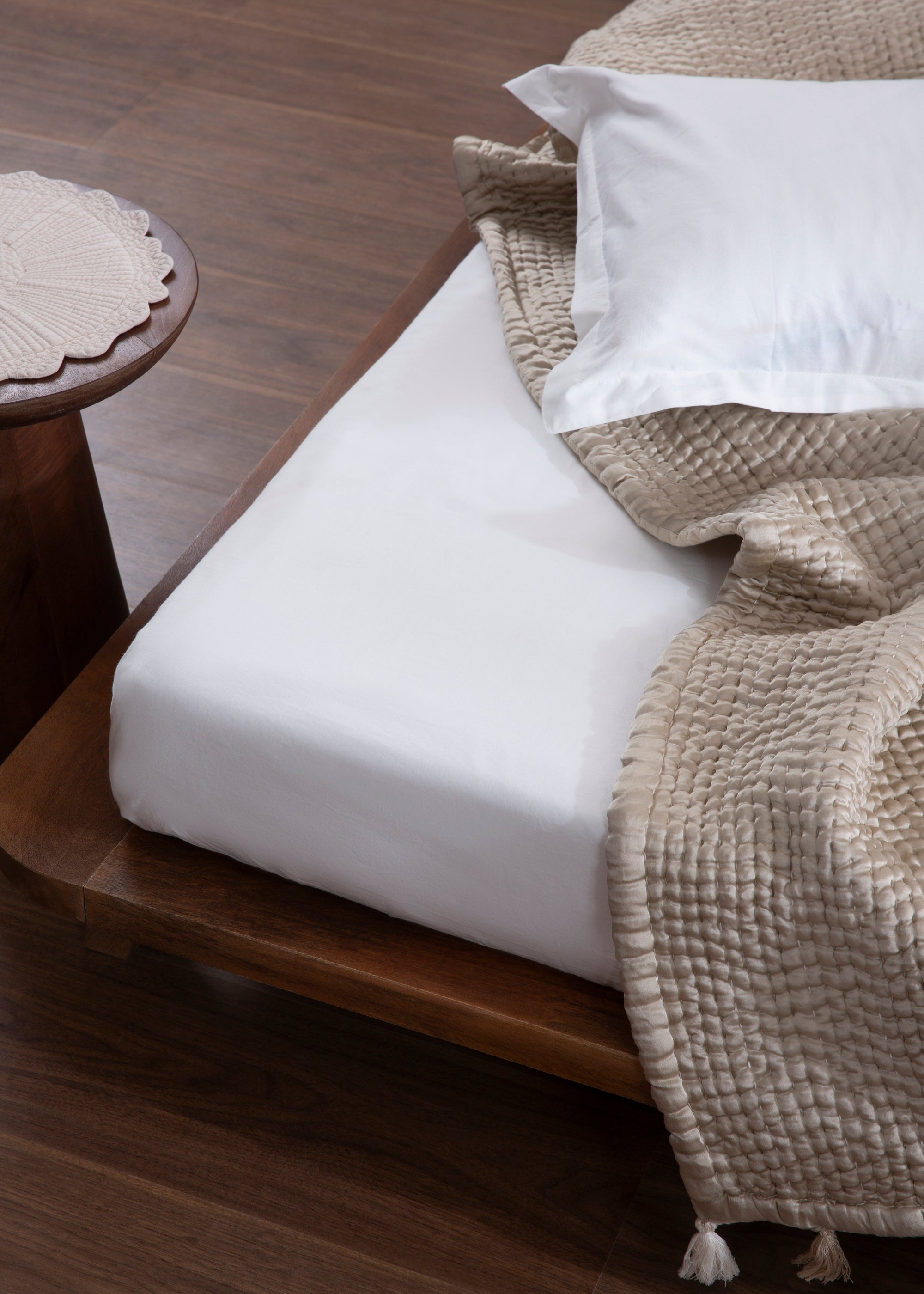 The Ethereal Silk Throw, a luxurious handwoven creation made from the finest mulberry silk. Its soft, rippled texture and delicate tassels exude refinement, draping effortlessly over a bed for a serene, elegant touch.