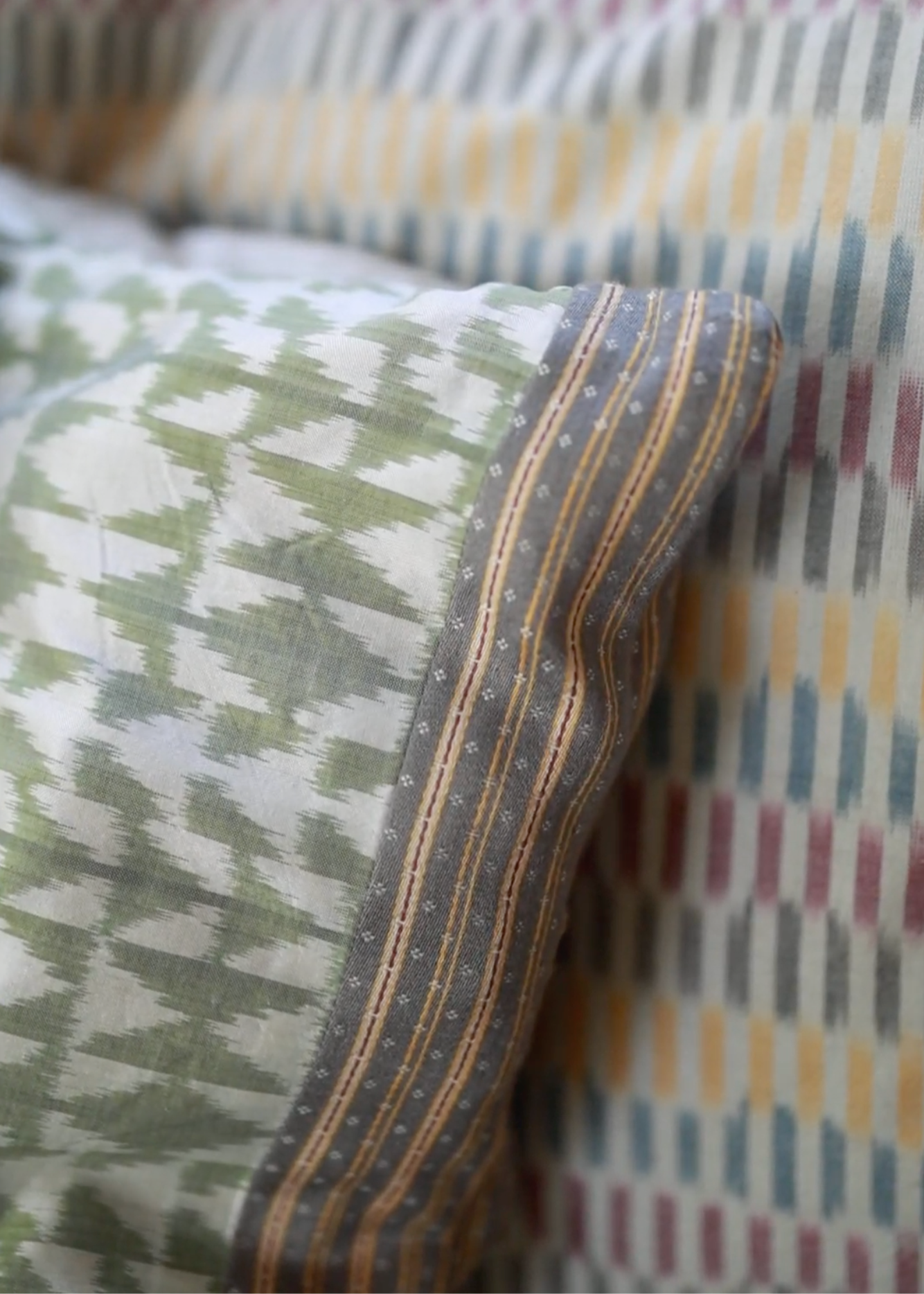 Vivia Cushion Cover, and Sofia Cushion Cover – A refined stack of handwoven silk and cotton cushion covers, each showcasing intricate craftsmanship and timeless design. The Mehira Silk Cushion Cover features a luminous weave with geometric accents, the Vivia Cushion Cover presents a soft herringbone-inspired pattern in earthy tones, and the Sofia Cushion Cover blends traditional motifs with delicate stripes. Perfectly layered, these cushions add depth, texture, and elegance to any spa