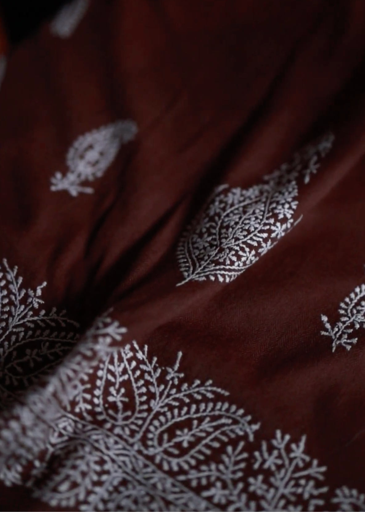 The Chambi Bedspread in Brown and White, a masterpiece of Kashmiri craftsmanship. Handwoven with care and adorned with delicate hand embroidery, its rich brown base is intricately decorated with traditional white paisley and floral motifs. A luxurious textile that embodies the artistry and heritage of Kashmir.