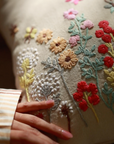Flourish Embroidery Cushion Cover – A beautifully handwoven cotton cushion cover featuring intricate hand embroidery. Every floral detail is meticulously stitched, bringing texture and artistry to life. A true celebration of craftsmanship, adding warmth and elegance to any space.