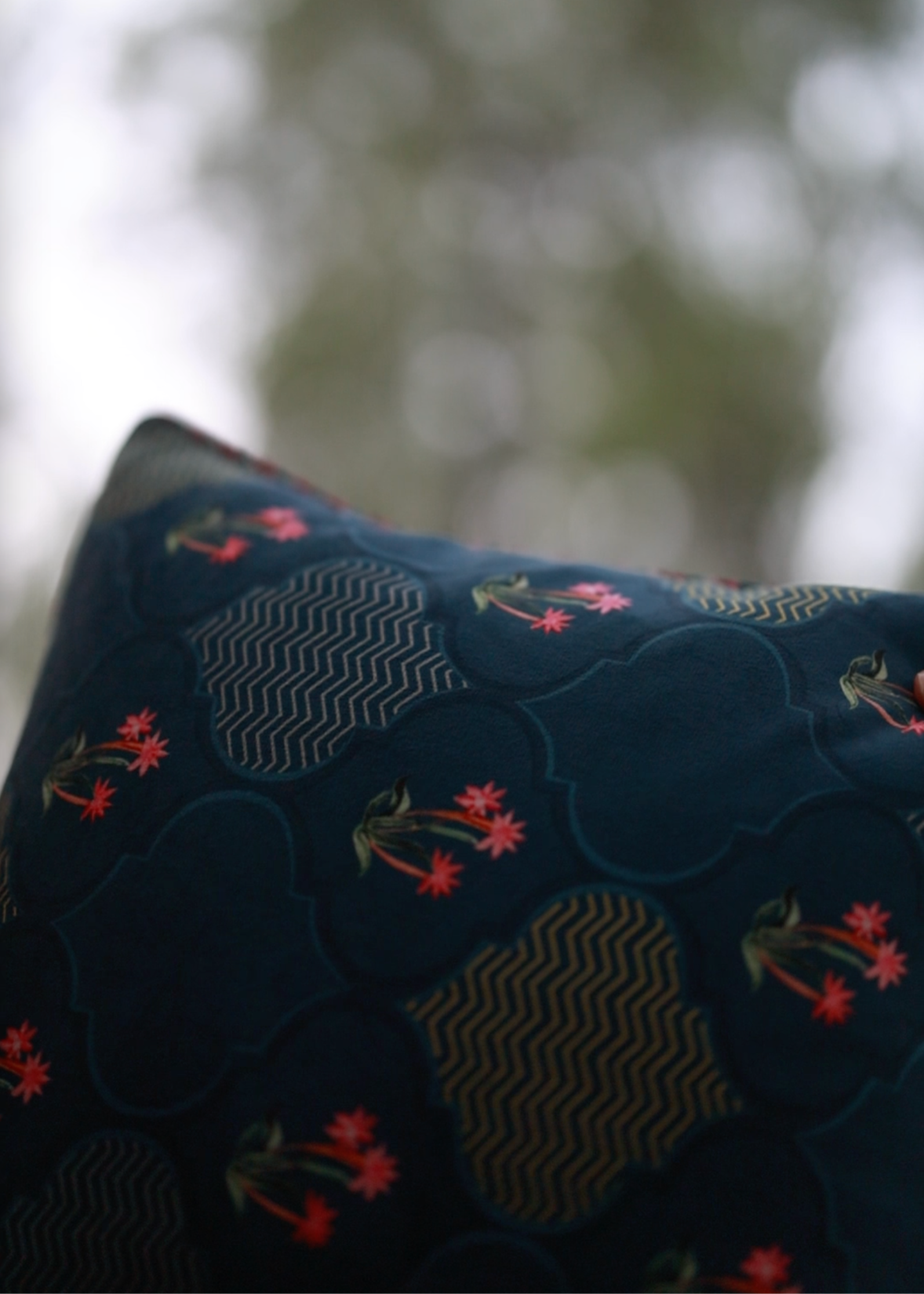 Nargis Cushion Cover – A luxurious fusion of cotton and velvet, this cushion cover features an intricate floral and geometric motif in rich navy blue, highlighted with delicate pink accents. Handcrafted with exceptional detail, its plush texture and vibrant tassel edging add a regal charm to any space.