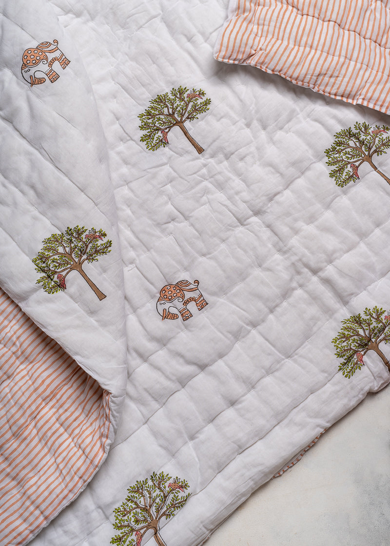 The Trees of Wonder Quilt, crafted from handwoven cotton, features intricate hand-block printed tree motifs that evoke a sense of natural serenity. The soft, quilted texture offers warmth and comfort, while the reversible striped pattern adds versatility to its timeless design. A perfect blend of artistry and coziness for an inviting bedroom.