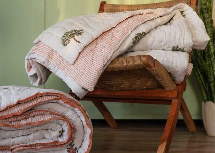 The Trees of Wonder Quilt, crafted from handwoven cotton, features intricate hand-block printed tree motifs that evoke a sense of natural serenity. The soft, quilted texture offers warmth and comfort, while the reversible striped pattern adds versatility to its timeless design. A perfect blend of artistry and coziness for an inviting bedroom.